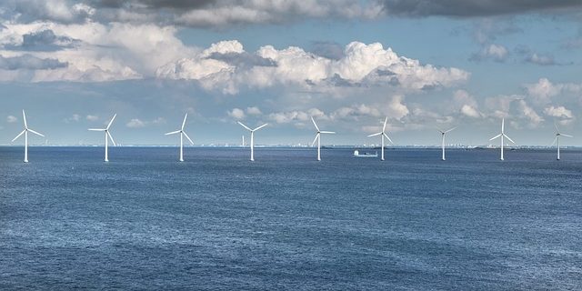 Windfarm Offshore wind turbines in a clear blue sea under a partly cloudy sky.